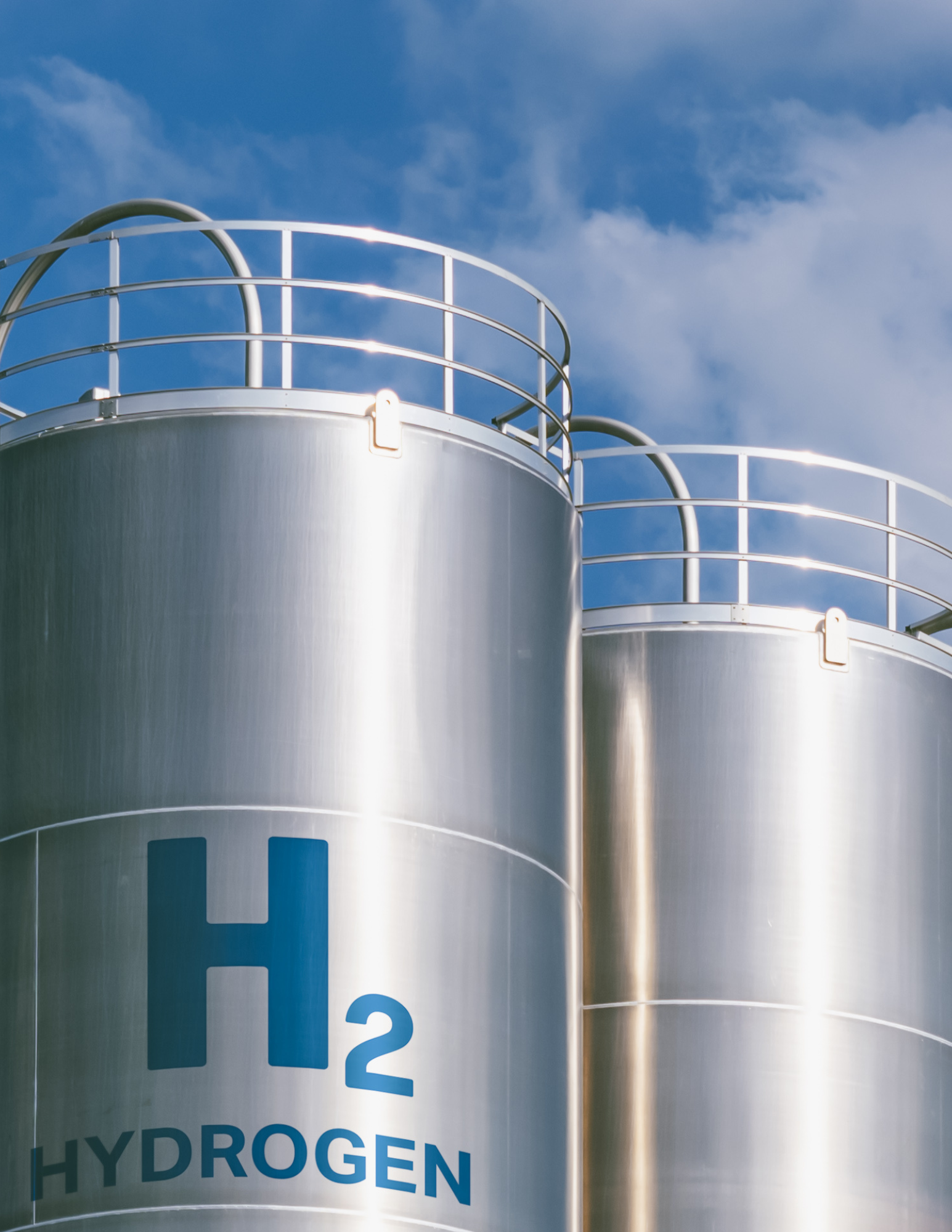 Two steel-colored hydrogen silos set against a blue sky with wispy clouds
